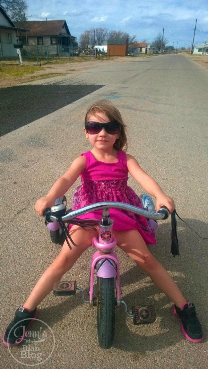 black and white picture of toddler on bike wearing sunglasses looking cool